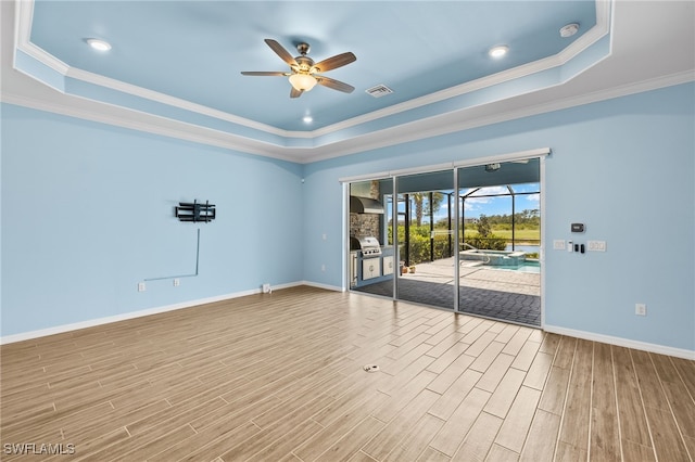 empty room with a ceiling fan, wood finished floors, visible vents, and a raised ceiling