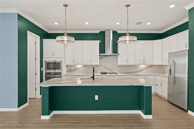 kitchen featuring ornamental molding, wall chimney range hood, wood finish floors, and appliances with stainless steel finishes
