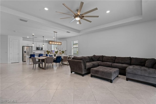 living room featuring visible vents, a ceiling fan, a tray ceiling, recessed lighting, and light tile patterned flooring