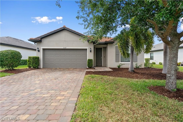single story home with a tiled roof, an attached garage, stucco siding, a front lawn, and decorative driveway