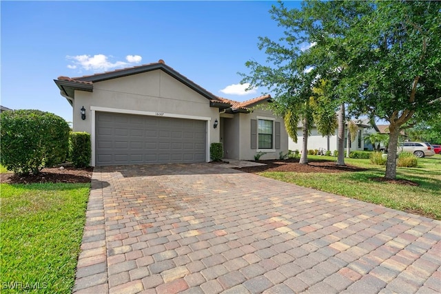 ranch-style home featuring a tiled roof, a garage, stucco siding, and decorative driveway
