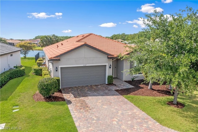 view of front of house featuring stucco siding, decorative driveway, a front yard, a tile roof, and an attached garage