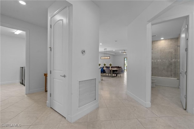 hall featuring light tile patterned flooring, baseboards, and visible vents