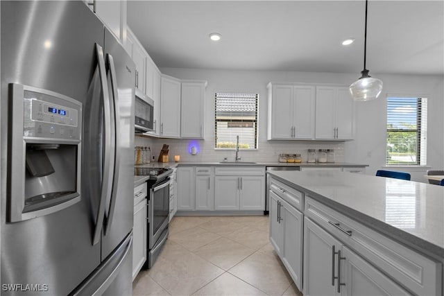 kitchen featuring plenty of natural light, a sink, appliances with stainless steel finishes, white cabinetry, and backsplash