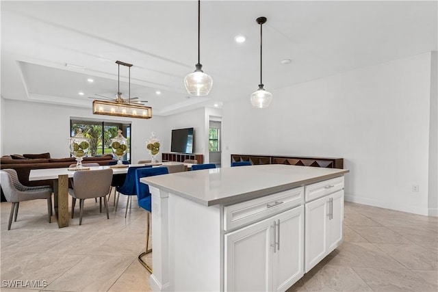 kitchen with a tray ceiling, white cabinets, a kitchen island, recessed lighting, and open floor plan