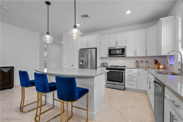 kitchen featuring a center island, backsplash, visible vents, stainless steel appliances, and a sink