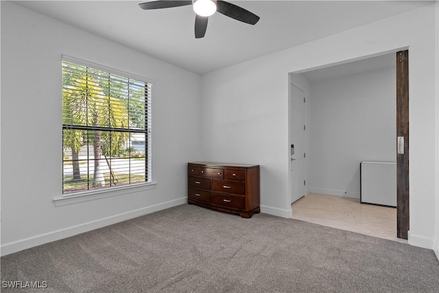 empty room with carpet, baseboards, a ceiling fan, and a healthy amount of sunlight