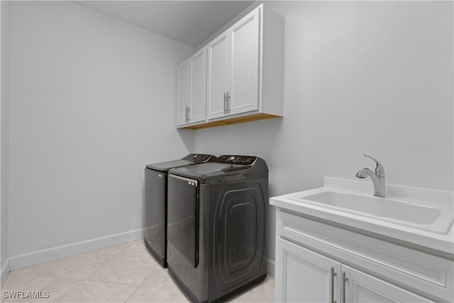clothes washing area with cabinet space, baseboards, separate washer and dryer, and a sink