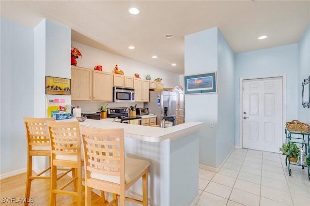 kitchen with light countertops, appliances with stainless steel finishes, a breakfast bar, a peninsula, and recessed lighting