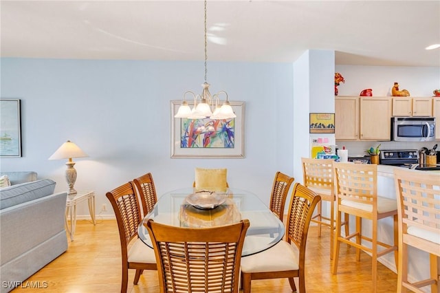 dining space with light wood-style floors, an inviting chandelier, and baseboards