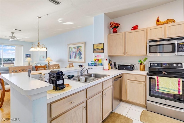 kitchen with a peninsula, light brown cabinetry, light countertops, a sink, and stainless steel appliances