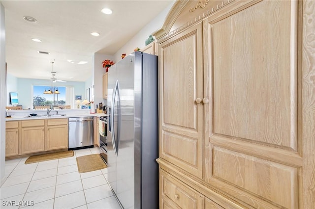kitchen featuring light tile patterned floors, a sink, light countertops, light brown cabinetry, and stainless steel appliances