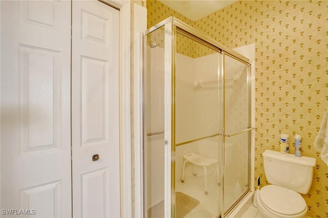 bathroom with toilet, wallpapered walls, and a stall shower