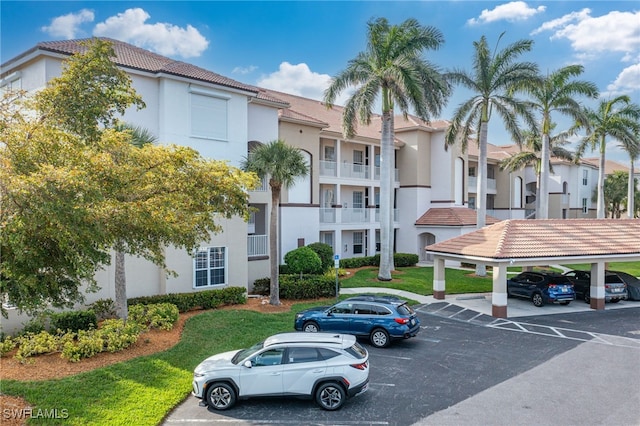 view of property with covered and uncovered parking and a residential view