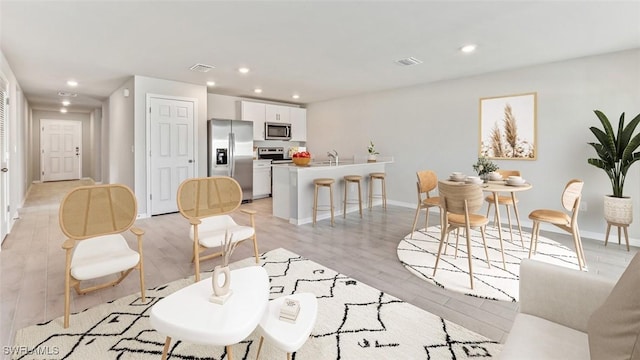 living room featuring light wood-style floors, recessed lighting, visible vents, and baseboards