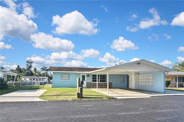 8150 Cleaves Rd, North Fort Myers, FL 33903 - view of front of home featuring a carport, stucco siding, fence, and a front lawn