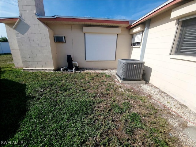 view of property exterior featuring concrete block siding, central AC, and a lawn