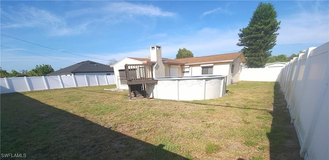 back of property with a yard, a fenced backyard, a fenced in pool, and a chimney