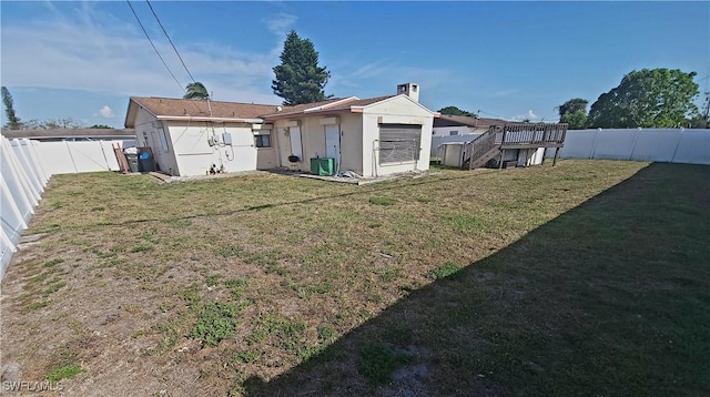 rear view of house with a fenced backyard, stucco siding, and a lawn