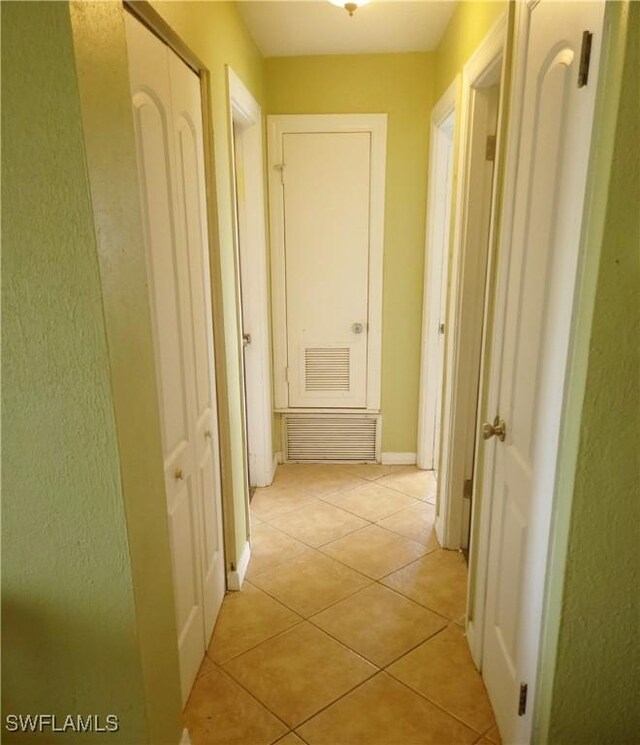 hallway featuring light tile patterned floors, visible vents, and baseboards