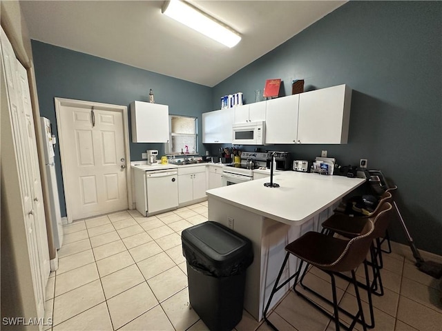 kitchen featuring a breakfast bar area, white cabinets, white appliances, and a peninsula