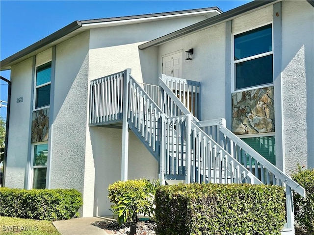 view of side of property featuring stucco siding and stairs