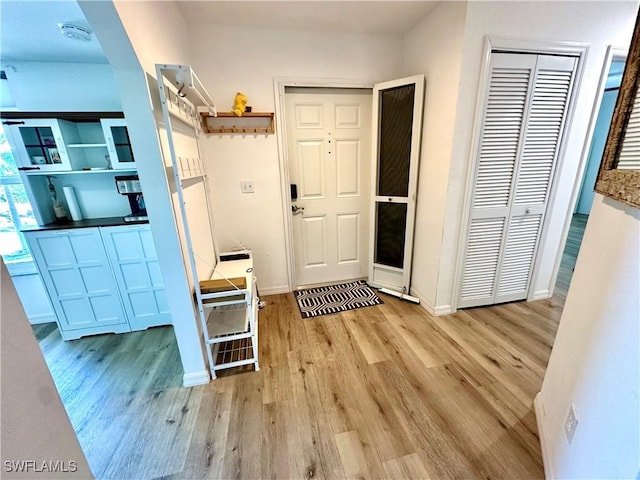 entrance foyer featuring light wood finished floors, arched walkways, and baseboards