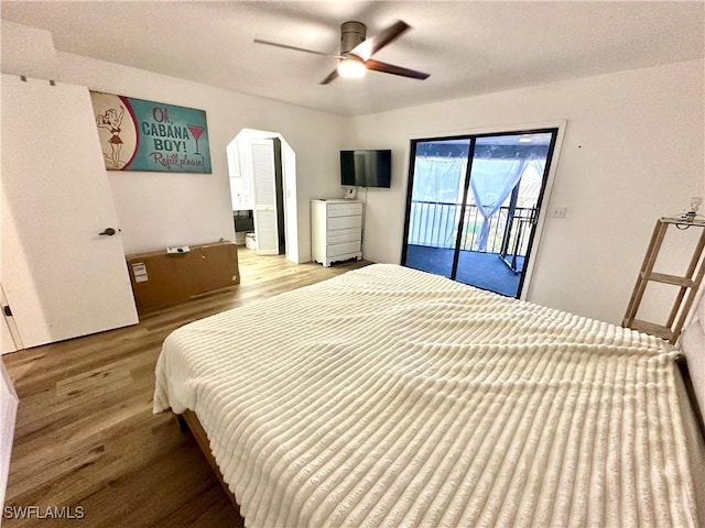 bedroom featuring access to exterior, a ceiling fan, wood finished floors, and arched walkways