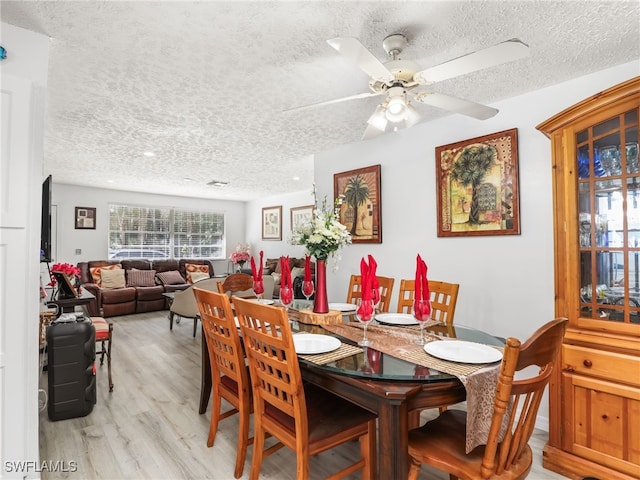 dining area featuring light wood-type flooring, ceiling fan, and a textured ceiling