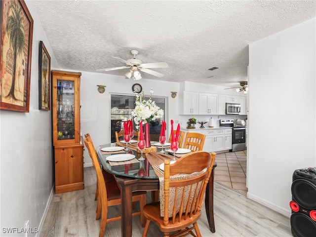 dining area with light wood-style flooring, a textured ceiling, ceiling fan, and baseboards