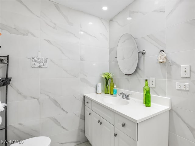 bathroom with toilet, tile walls, recessed lighting, and vanity