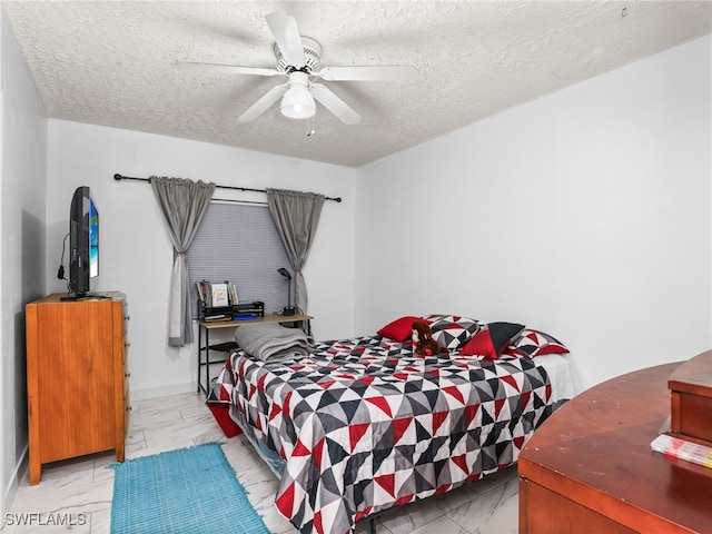 bedroom with a ceiling fan, marble finish floor, and a textured ceiling