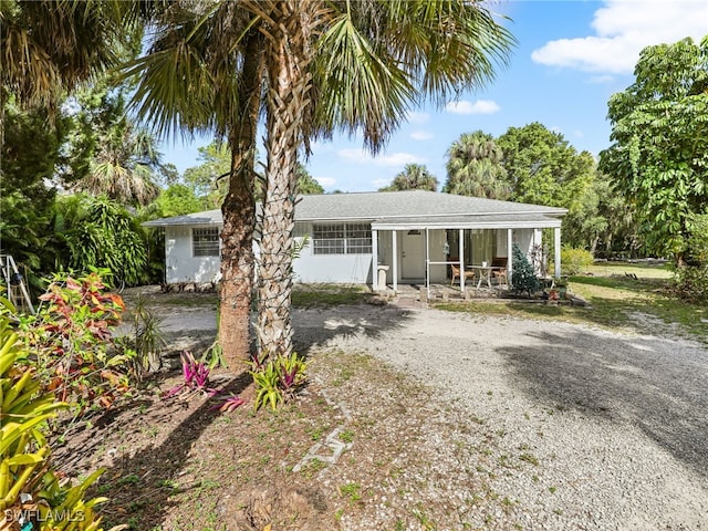 view of front of home with a sunroom and gravel driveway