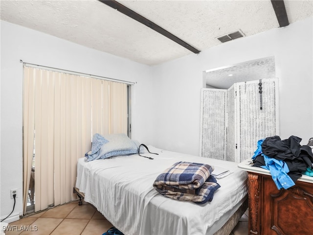 bedroom featuring tile patterned flooring, visible vents, and a textured ceiling