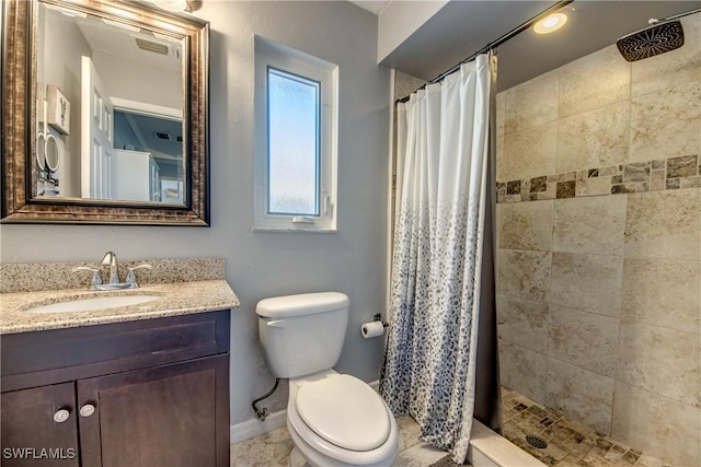 full bath featuring toilet, tiled shower, vanity, and baseboards