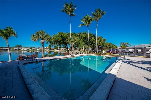 pool featuring a patio area, fence, and a water view