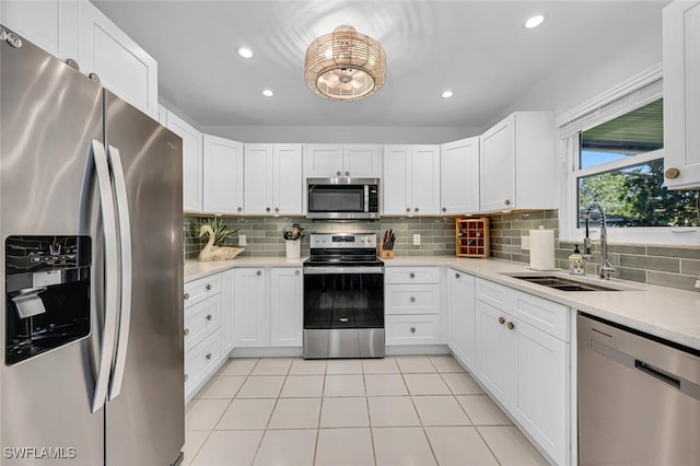 kitchen featuring appliances with stainless steel finishes, light tile patterned floors, light countertops, decorative backsplash, and a sink