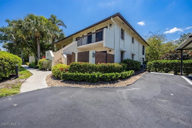 exterior space with uncovered parking, stucco siding, and cooling unit