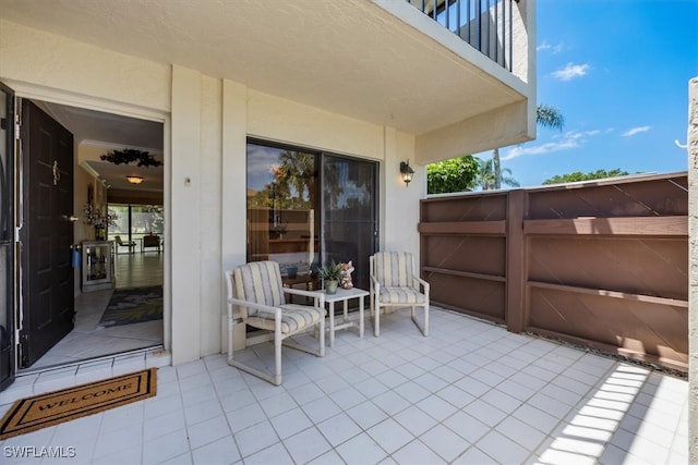 view of patio featuring fence and a balcony