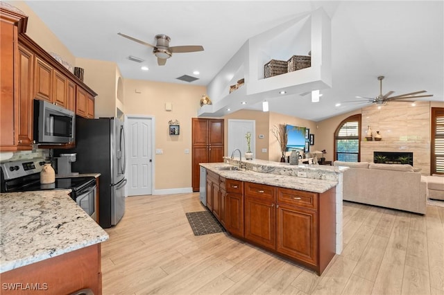 kitchen with a sink, ceiling fan, brown cabinets, and stainless steel appliances