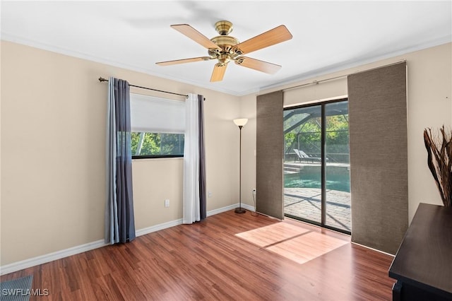 spare room featuring plenty of natural light, baseboards, a ceiling fan, and wood finished floors