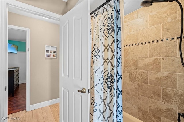 bathroom featuring baseboards, a shower with curtain, and wood finished floors