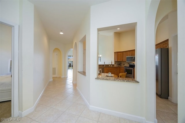 3057 Driftwood Way Unit 4004, Naples, FL 34109 - hall with arched walkways, light tile patterned flooring, a sink, baseboards, and recessed lighting