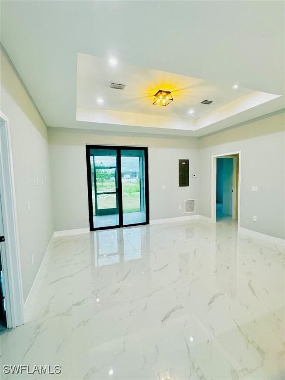 spare room featuring visible vents, baseboards, and a raised ceiling