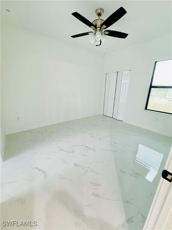unfurnished room with marble finish floor and ceiling fan