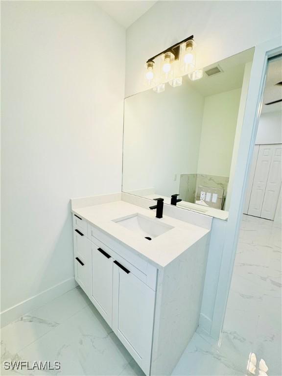 bathroom featuring visible vents, marble finish floor, baseboards, and vanity