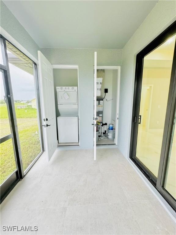 unfurnished sunroom featuring stacked washer and dryer
