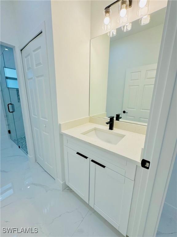 full bath with marble finish floor, vanity, and a stall shower