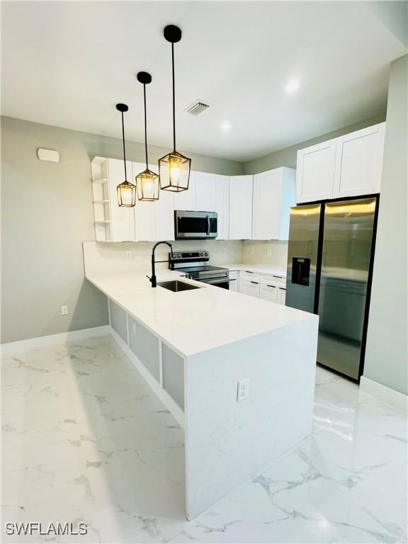 kitchen with a peninsula, visible vents, stainless steel appliances, marble finish floor, and a sink