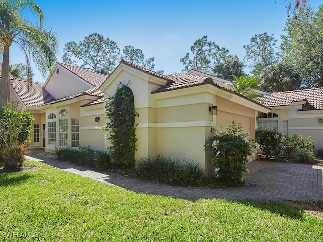 114 Amblewood Ln Unit 9-903, Naples, FL 34105 - view of home's exterior with a garage, stucco siding, a tile roof, and a lawn